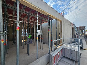 Gradbišče Zdravstveni center Podpeč Stropni opaž RINGER z rdečimi opažnimi ploščami in kovinskimi podpornimi stojkami v notranjosti zdravstvenega centra Podpeč