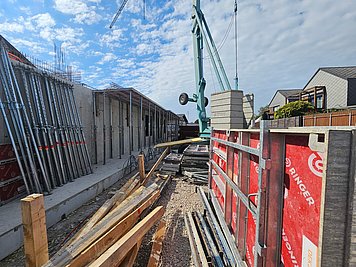 Gradbišče Zdravstveni center Podpeč Opažni sistem RINGER AluDEK ob betonski steni na gradbišču zdravstvenega centra Podpeč, s pripravljenimi opažnimi elementi in gradbenim materialom