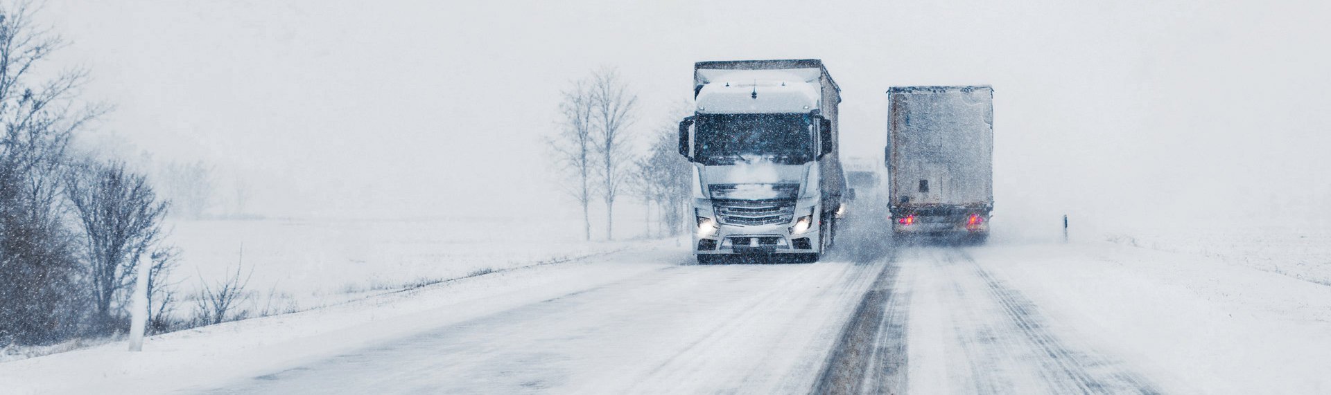 LKW unterwegs in einer winterlichen Landschaft auf einer Schneefahrbahn