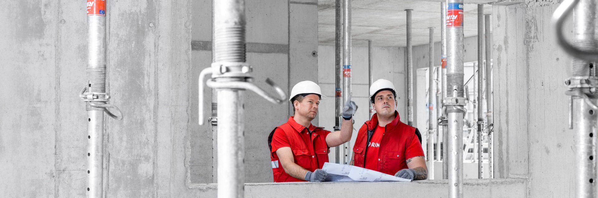 Zwei Arbeiter von Ringer GmbH bei der Inspektion von normgerechten Deckenstützen auf einer Baustelle