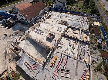 Pogled na gradbišče objekta DC208 iz zraka. Pogled iz zraka na gradbišče večstanovanjskega objekta DC208 v Ljubljani na Rudniku z vidnimi temelji, betonskimi ploščami in opažnimi elementi RINGER.